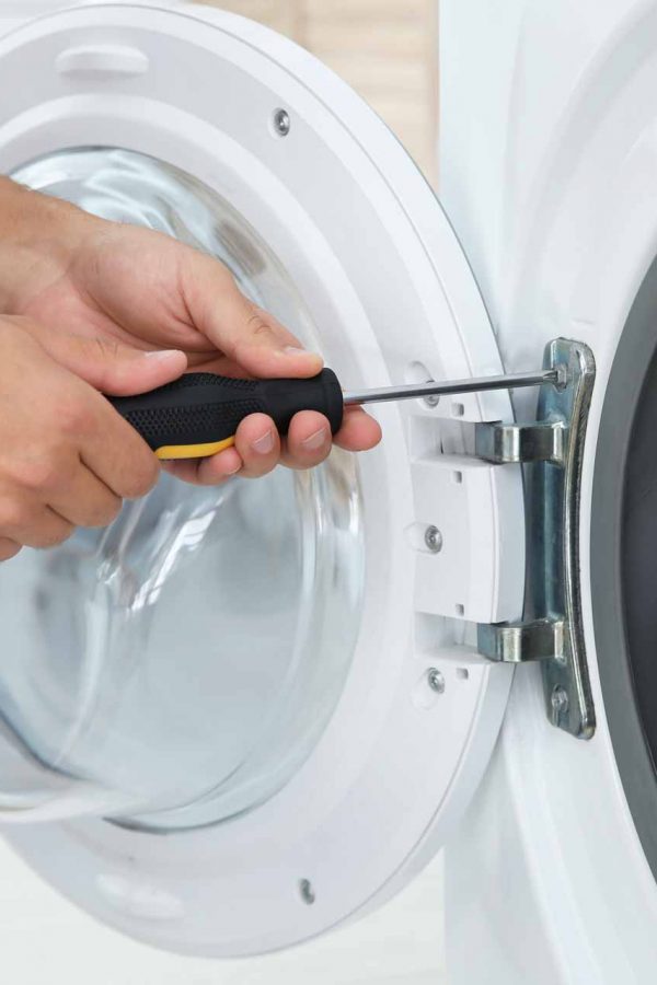 Close-up shot of appliance repair technician fastening door on dryer