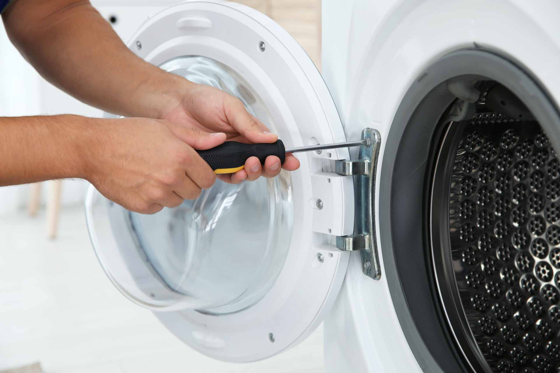 Close-up shot of appliance repair technician fastening door on dryer