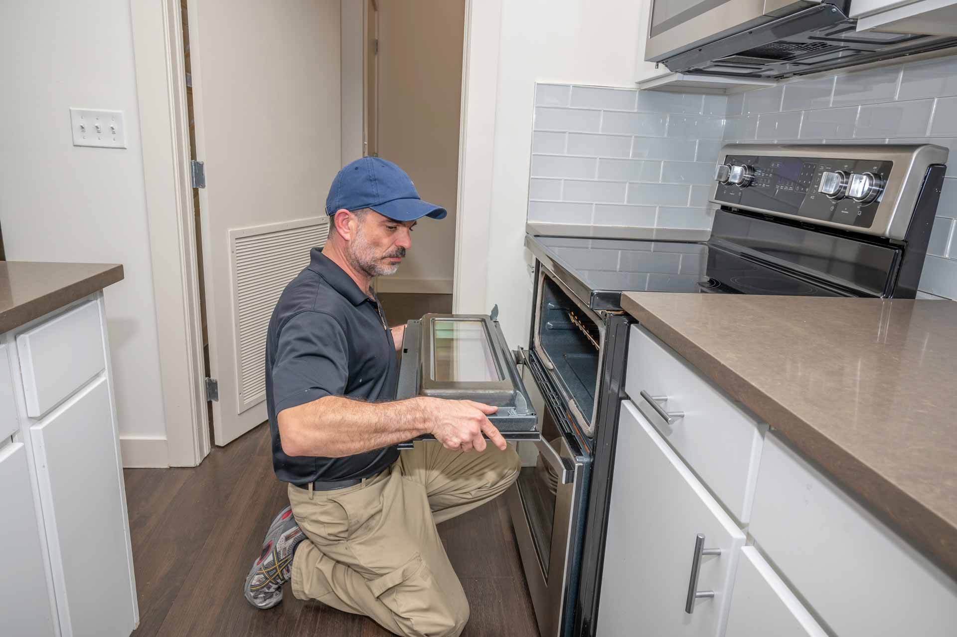 Appliance repair technician removes door from faulty oven to facilitate repair